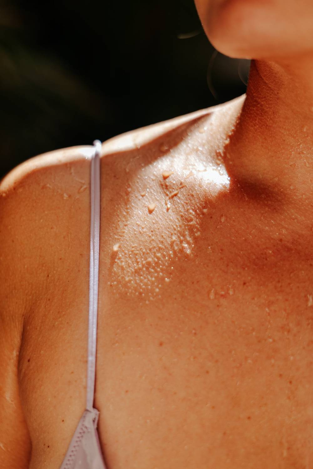 Sunlit skin with water droplets along the collarbone